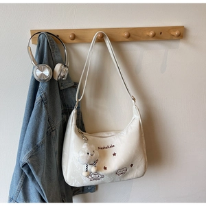 Detail of off-white shoulder bag with cartoon cat embroidery and plush cloud charm