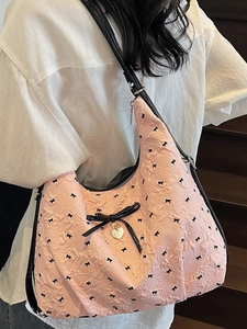 Borsa hobo trapuntata rosa con fiocchi neri e ciondolo a cuore indossata da modella
