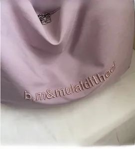 Detail of light purple canvas bag showing fine fabric texture and pink embroidery