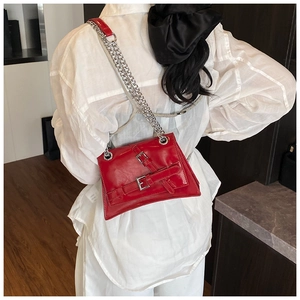 Détail du sac à bandoulière en cuir verni rouge avec boucles et chaîne argentée