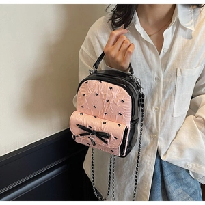 Detail of mini black and pink seersucker backpack with bow accents and silver chain