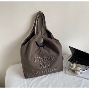 Gros plan du cabas marron foncé avec broderie 'Chase My Dreams' et texture en toile fine