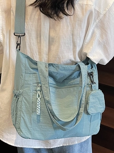 Morandi blue large nylon tote bag with mini coin purse shown on a model in a minimalist setting