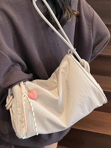 Minimalist white pillow canvas crossbody bag with pink heart pendant on wooden stairs