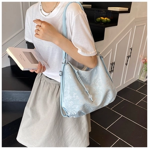 Detail of light blue Hobo bag featuring embossed floral texture and drawstring accents