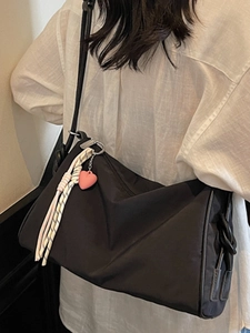 Minimalist black canvas pillow crossbody bag with pink heart pendant and woven tassel