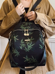 Sac à dos noir imperméable à motif de feuilles vertes et détails dorés sur modèle