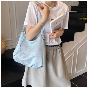 Detailed view of light blue hobo bag with intricate silver jacquard embroidery texture