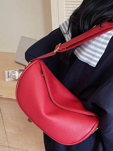 Sacoche selle chic en cuir rouge avec large bandoulière portée par un mannequin dans une pièce