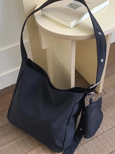 Grande borsa tote nera classica con tracolla larga e mini custodia su uno sgabello di legno