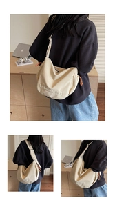 Close-up of beige canvas shoulder bag with embroidered letters and orange cord detail