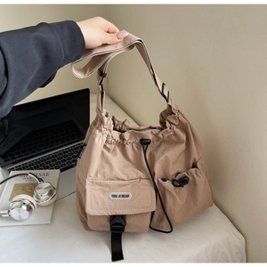 Detail of khaki nylon tote bag showing multiple functional pockets and drawstring closure