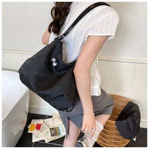 Detail of black jacquard tote bag with metal buckle strap on a fashion model