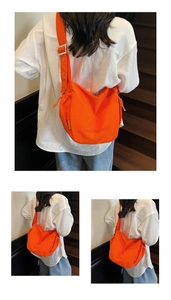 Detail of bright orange canvas crossbody bag with adjustable strap and logo embroidery