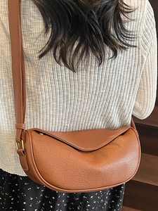 Sac hobo marron à motif litchi avec bandoulière réglable porté par un mannequin en style chic