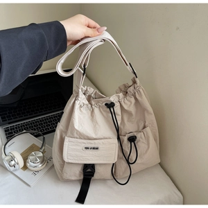 Detail of light beige nylon tote bag with drawstring closure on a desk with a laptop
