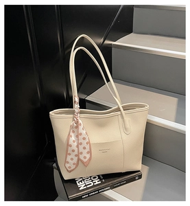 Detail of beige pebble leather tote bag featuring a decorative polka dot silk scarf