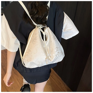 Detail of white jacquard backpack showing floral texture and drawstring closure system