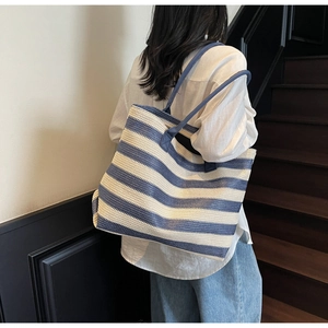 Detail view of woven straw tote bag featuring blue and white stripes for beach holidays