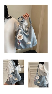 Detalle del bolso hobo de lona azul claro con un colgante decorativo de cuentas