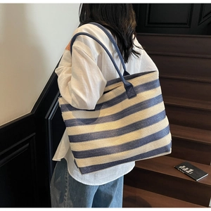 Detail of blue and white striped woven tote bag with smooth texture and long shoulder straps