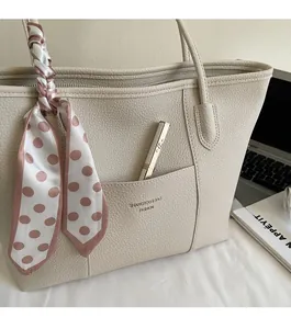 Beige pebble leather tote bag featuring a decorative polka dot scarf on the handle