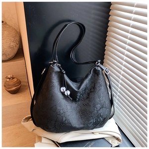 Detail of black jacquard tote bag with floral patterns and beaded charm accessory