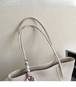 Detail of lychee pattern leather tote bag with elegant striped silk scarf decoration