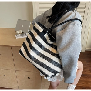 Detail of large woven tote bag with bold black and white stripes and sturdy black straps