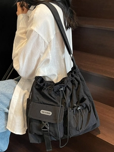 Black large capacity drawstring canvas tote bag worn as crossbody shoulder bag