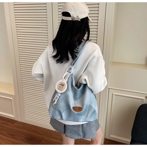 Detalle de bolso tote de lona con parche de cuero y colgantes coloridos de moda