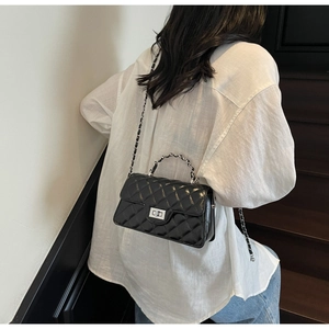 Detail of black quilted leather shoulder bag with metallic twist lock and chain strap