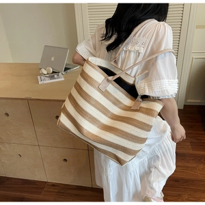 Lifestyle shot of large woven striped tote bag worn on shoulder in modern interior