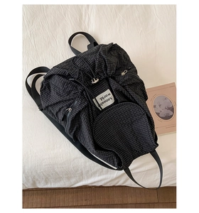 Detailansicht des schwarz-weißen Karorucksacks mit Kordelzug und seitlicher Reißverschlusstasche