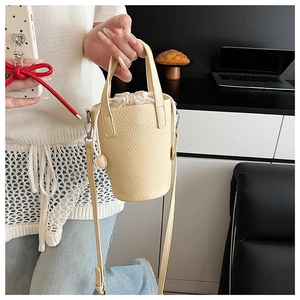Détail du sac seau en cuir crème à grain lychee avec cordon de serrage et poignée