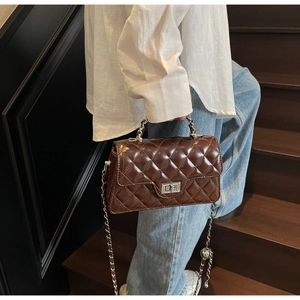 Detailed view of dark brown quilted leather bag with silver twist lock and metal handle