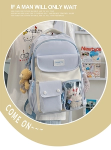 Detail of blue and white school backpack with transparent pocket and plush teddy charm