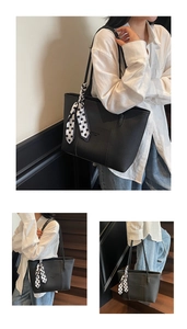 Detail of black pebbled leather tote bag featuring a decorative polka dot scarf accessory