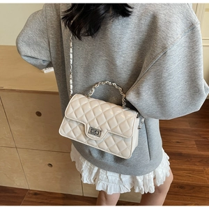 Detail of quilted beige chain bag featuring silver twist lock and woven leather strap