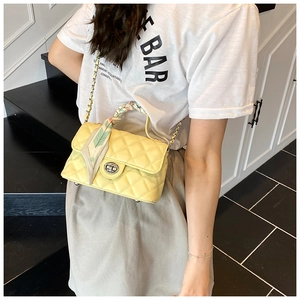 Detail of yellow quilted crossbody bag with silk scarf handle and metal twist lock