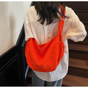 Detail of high-capacity orange canvas crossbody bag with delicate embroidery and wide strap