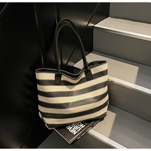 Detail of black and white striped woven tote bag with long handles on a modern step