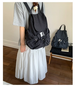 Detail des karierten Nylon-Rucksacks mit Kordelzug und Awesome world Stoffaufnäher