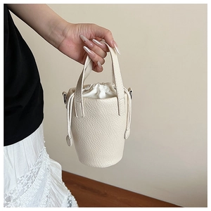 Détail d'un sac seau en cuir grainé blanc crème avec fermeture par cordon coulissant