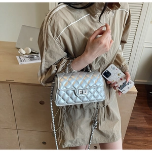 Silver quilted chain bag with turn-lock closure shown on a model in a modern office setting