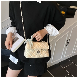 Close-up of beige quilted crossbody bag with silk scarf handle on model in indoor setting