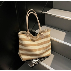 Close-up of beige and brown striped straw tote bag showing woven texture and soft handles