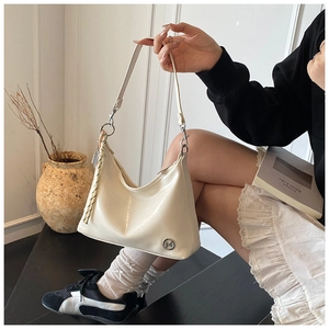 Detailed close-up of a cream crescent tote bag with glossy leather and metal ring accents