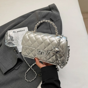 Detail of silver quilted chain bag with metallic finish and elegant twist lock closure