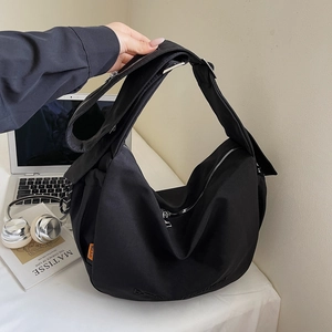 Detail of black canvas crossbody bag showing metal zipper and adjustable wide strap